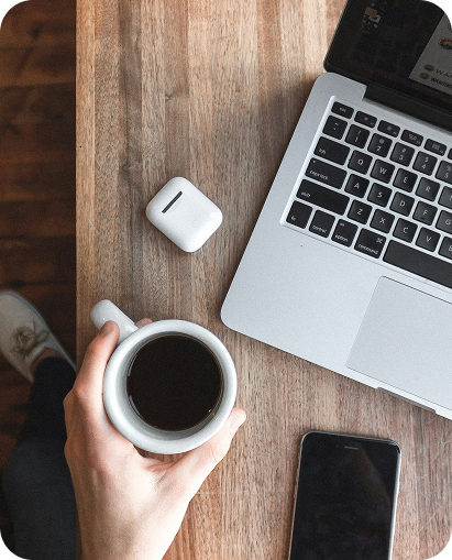 Person working at a desk with laptop, coffee, and phone