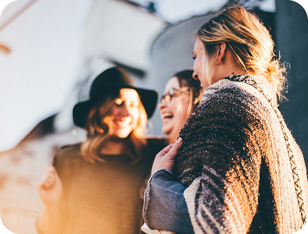 Three people laughing together outdoors